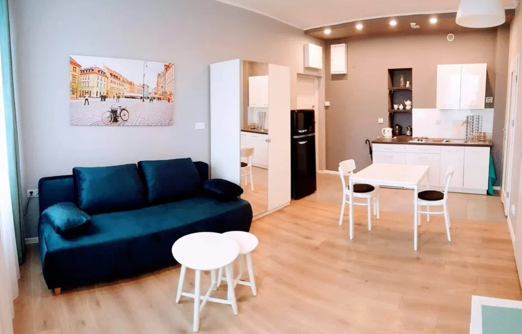 Salon z granatową sofą i aneksem kuchennym